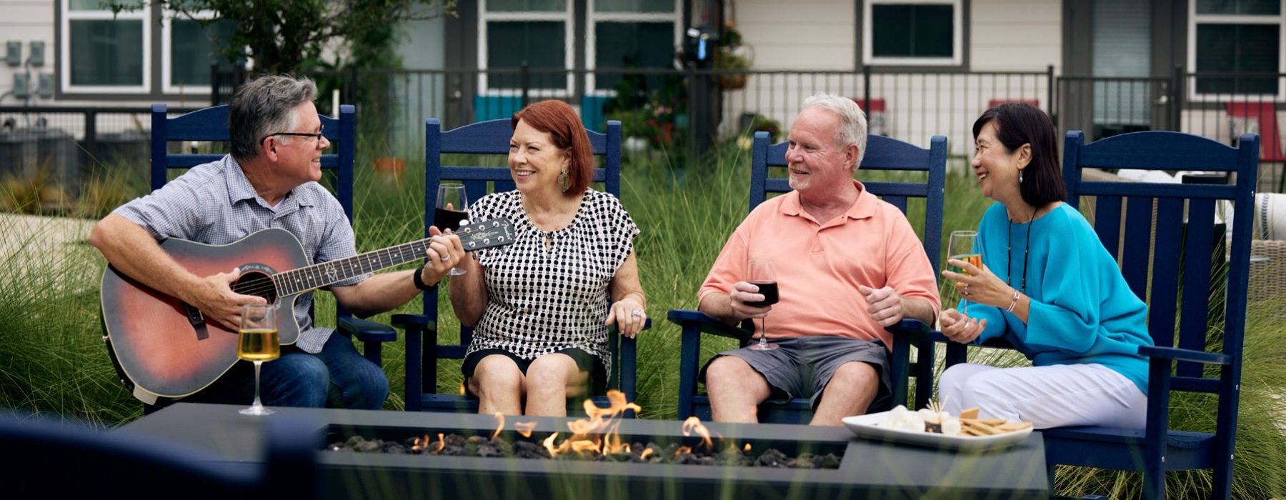 The lifestyle you've been waiting for. people sitting around fire and a man playing a guitar